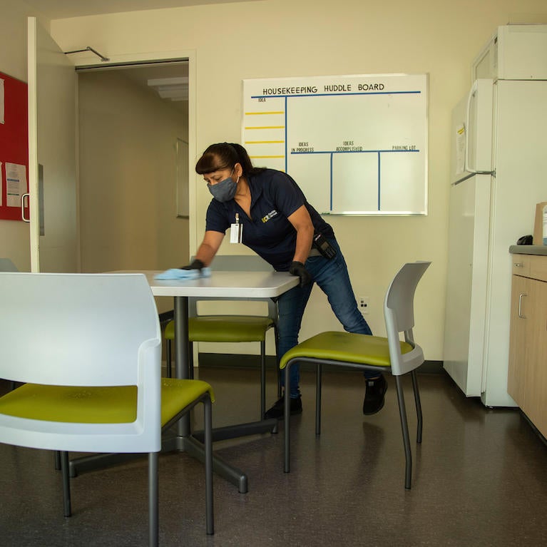 Senior Custodian Fabiola Aguirre, with Facilities Services, disinfects a table in a break room at the Glen Mor Apartments at UCR on April 30, 2020. (UCR/Stan Lim)