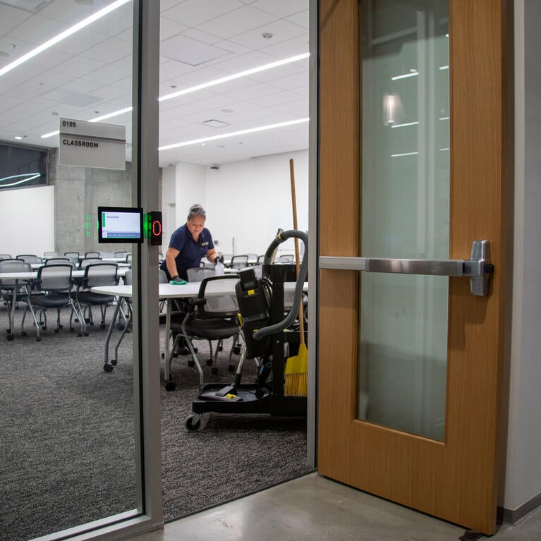 Custodian wipes down tables in a classroom