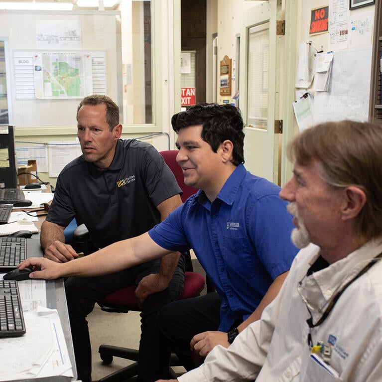 Hondo with two colleagues reviewing a computer monitor