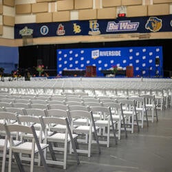 Indoor seating of empty white chairs facing a stage