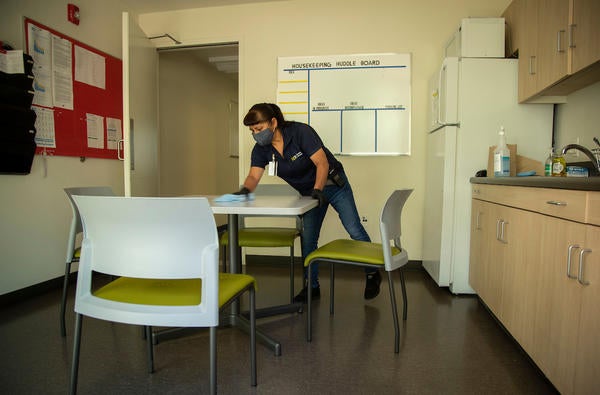 Senior Custodian Fabiola Aguirre, with Facilities Services, disinfects a table in a break room at the Glen Mor Apartments at UCR on April 30, 2020. (UCR/Stan Lim)