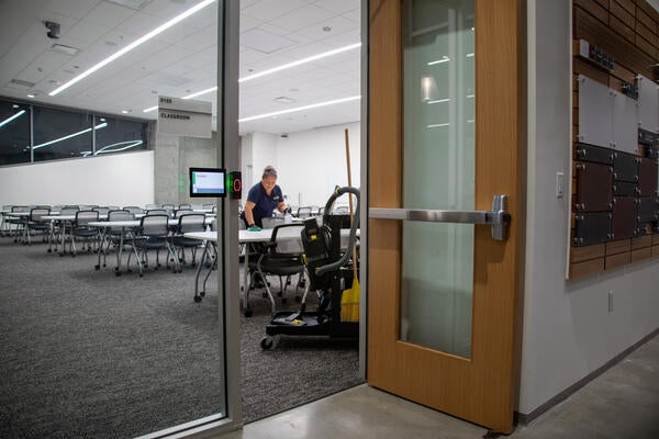 Custodian wipes down tables in a classroom