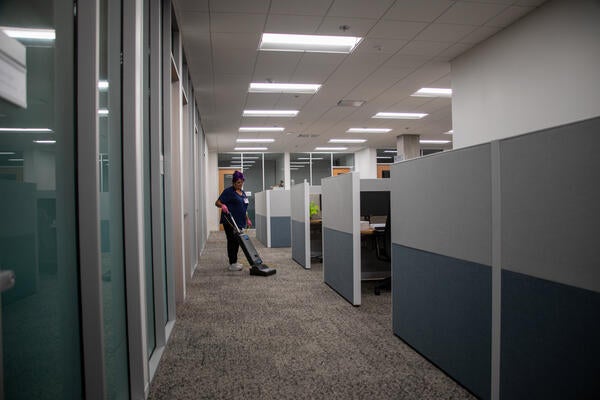 Custodian vacuuming around office cubicles