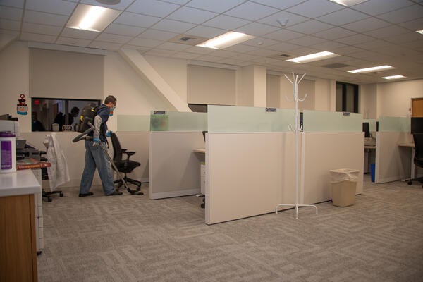 Custodian with vacuum backpack cleaning office cubicles