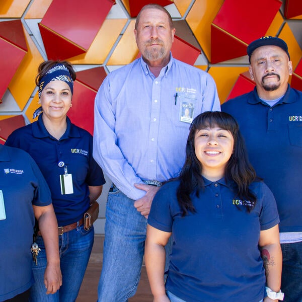 Custodians standing in front of a red and orange background