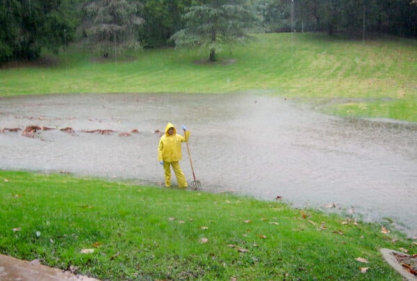 A groundskeeper surveys a rain-swollen field of grass