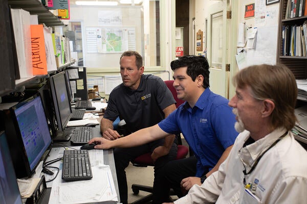 Hondo with two colleagues reviewing a computer monitor