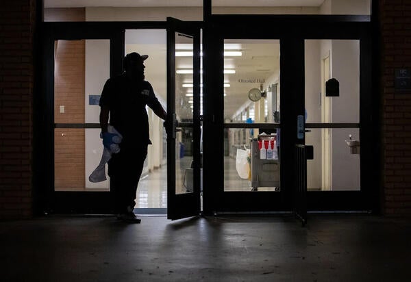 Custodial leaving building with supplies at night