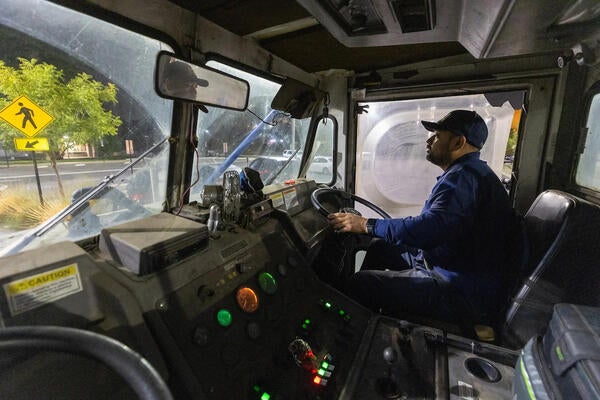 Man driving a street sweeper at night