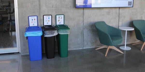 Three bins against a wall next to chairs and a TV