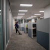 A custodian vacuuming around office cubicles