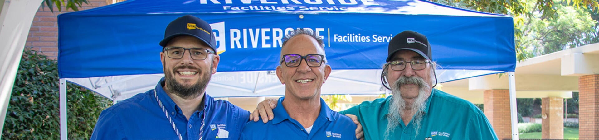 Three staff smiling in front of an outdoor booth