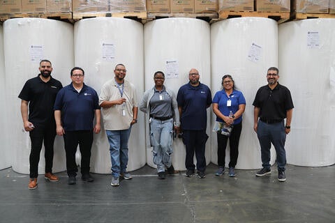 People standing in front of colossal paper rolls