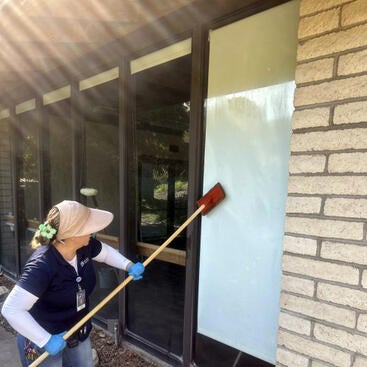 Custodian cleaning window
