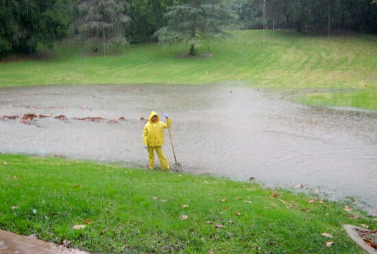 A groundskeeper surveys a rain-swollen field of grass