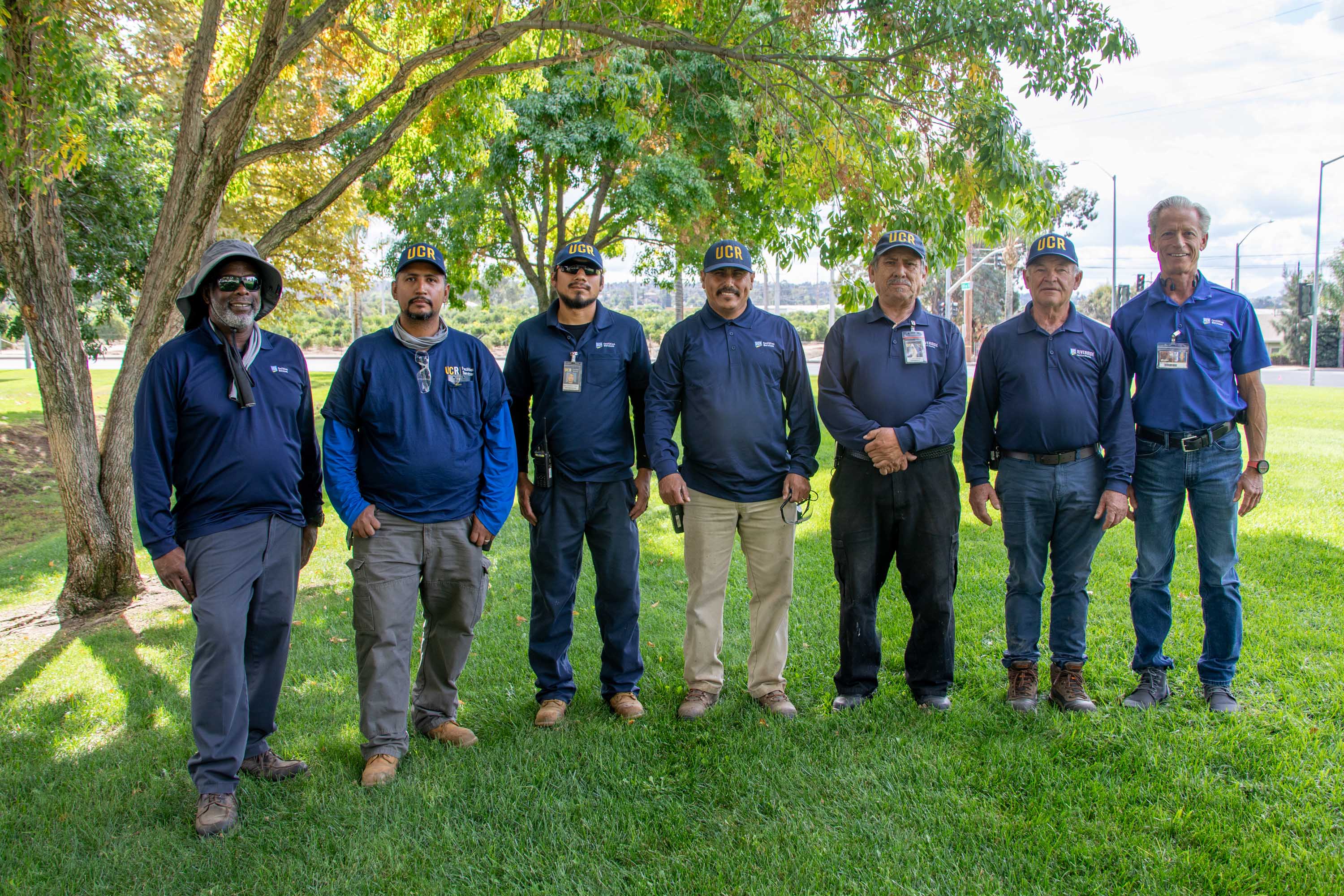 A team of seven landscape employees in a grassy area